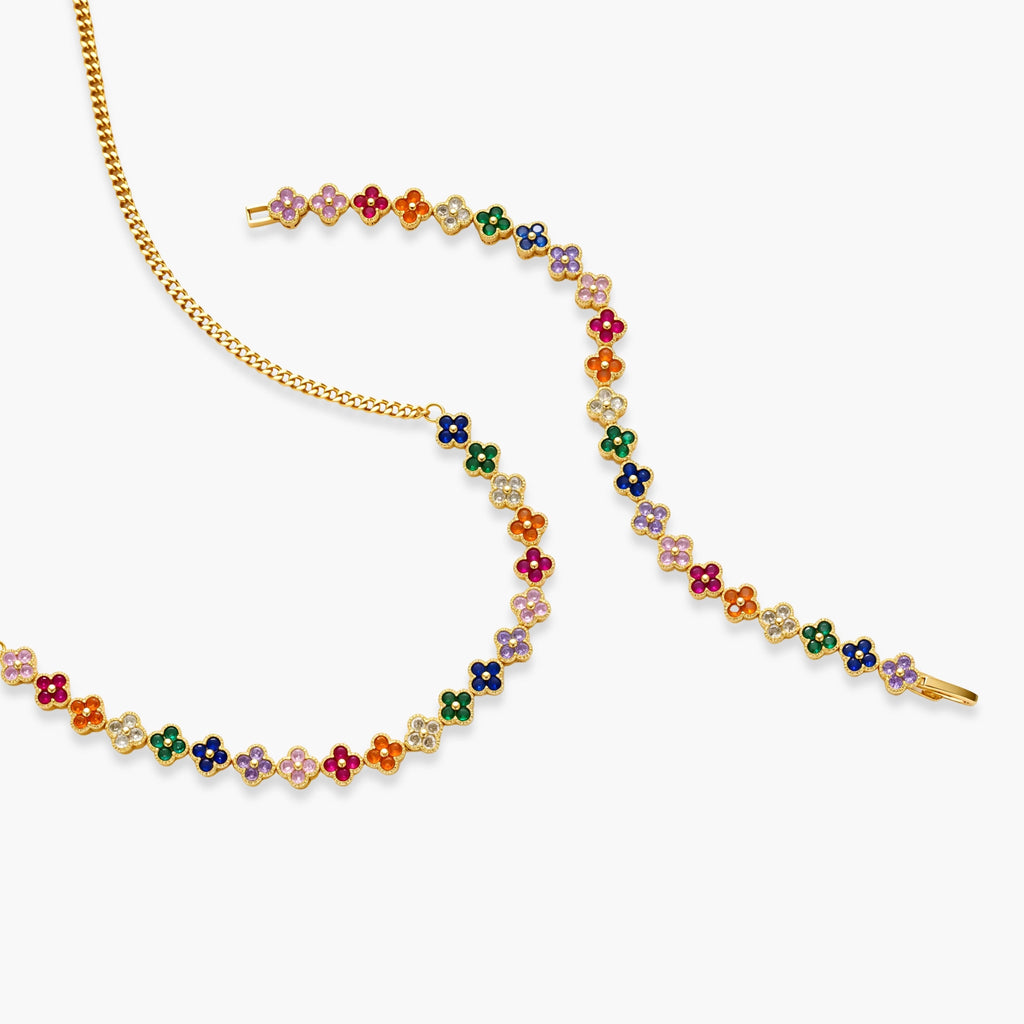 Colorful four-leaf clover jewelry set with rainbow cubic zirconia stones in gold-plated setting on white background