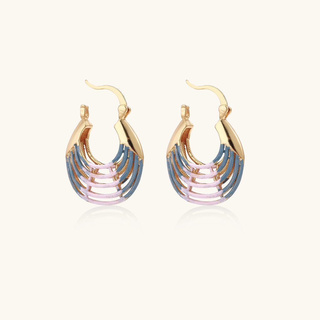 Gold hoop earrings with gradient blue-to-pink enamel in ribbed fan design on beige background