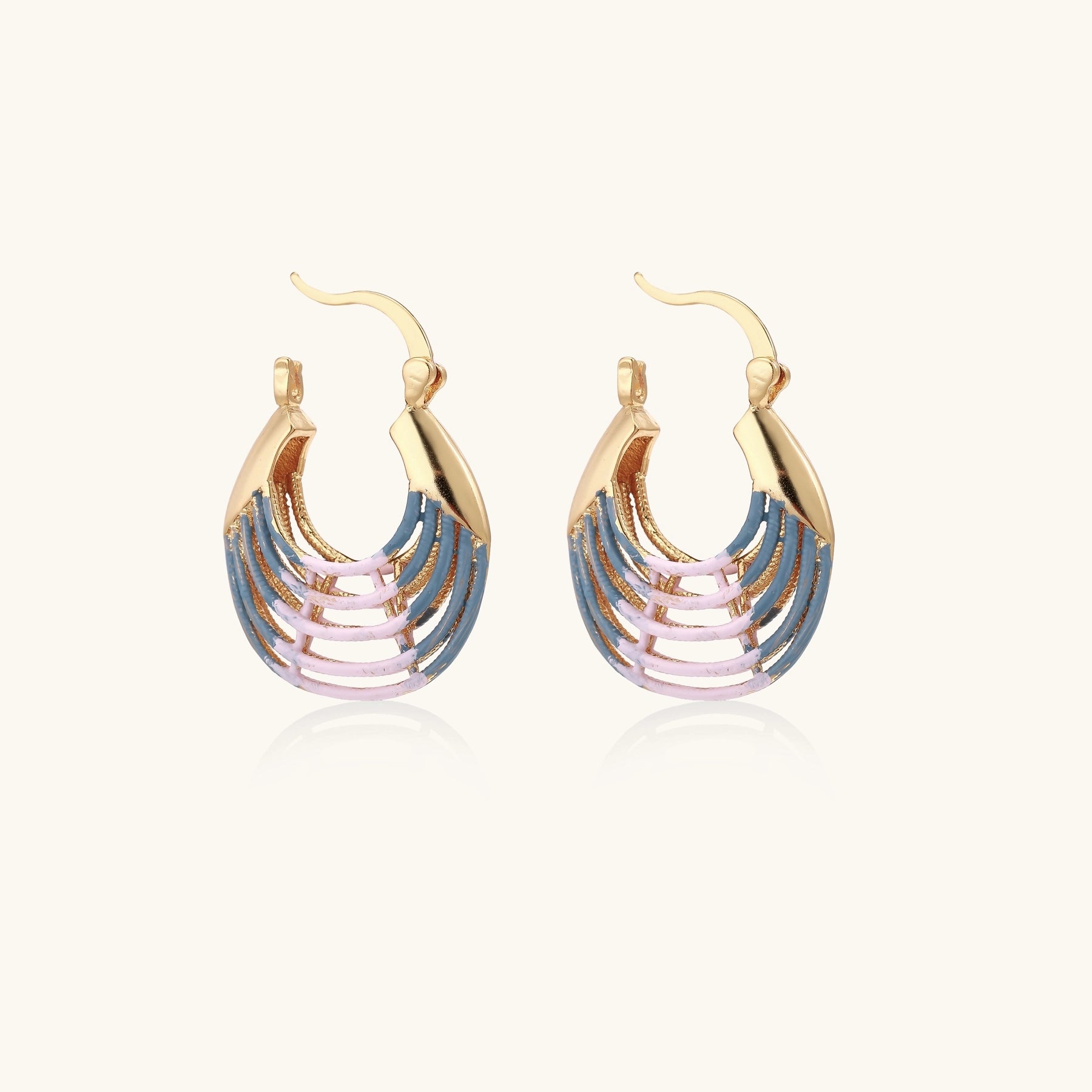 Gold hoop earrings with gradient blue-to-pink enamel in ribbed fan design on beige background