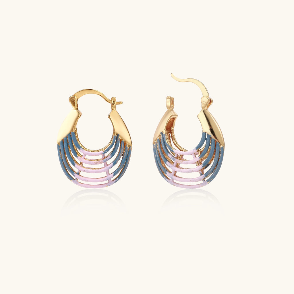 Gold hoop earrings with gradient blue-to-pink enamel in ribbed fan design on beige background
