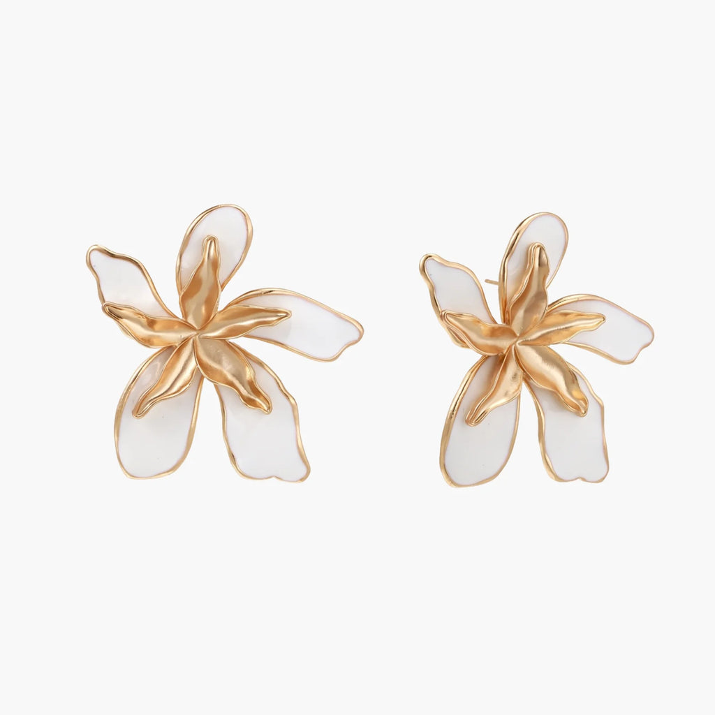 White enamel tropical flower earrings with sculptural gold-plated center and organic petal design on cream background
