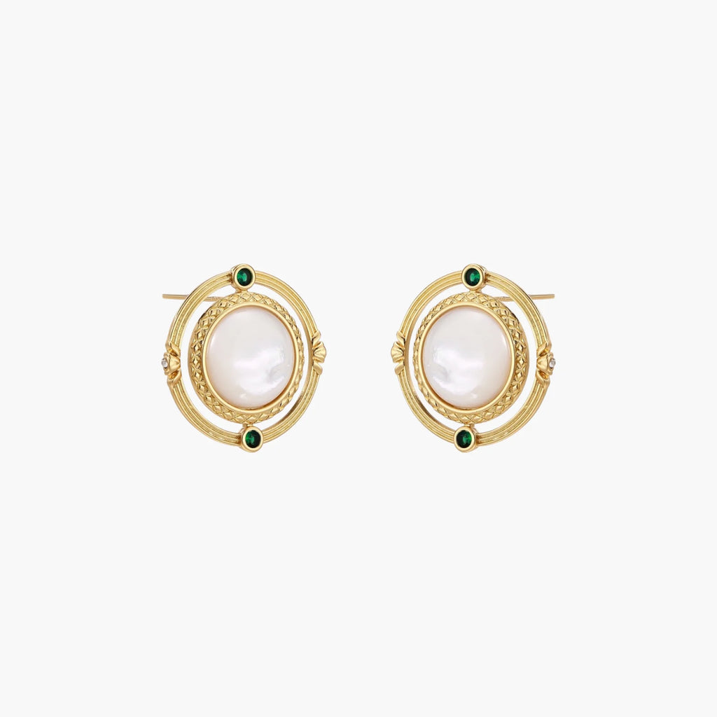 Circular gold stud earrings with iridescent mother-of-pearl center and green zirconia accents on cream background.