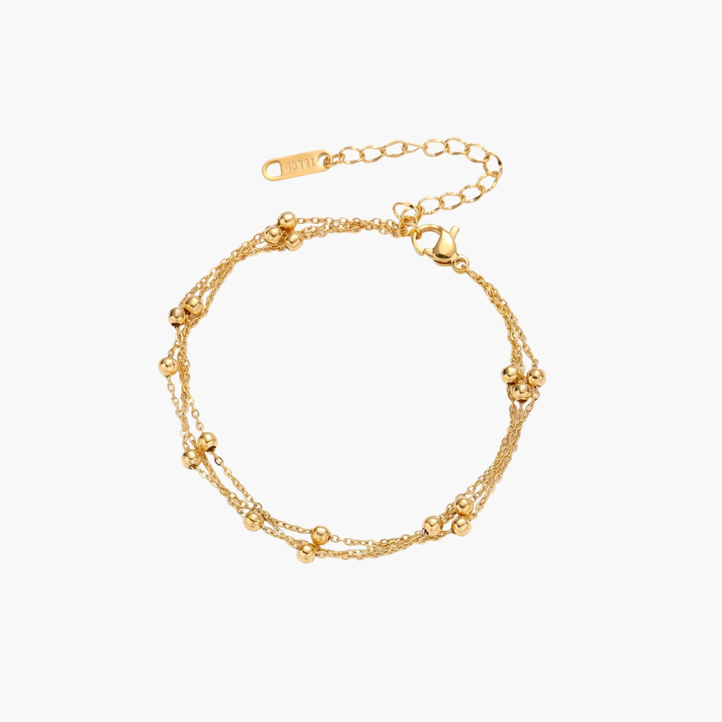 Three-strand gold-plated bracelet with clustered ball beads and adjustable clasp on cream background