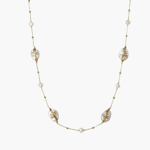 Long gold chain necklace with baroque pearls wrapped in leaf designs and small freshwater pearls spaced along the strand