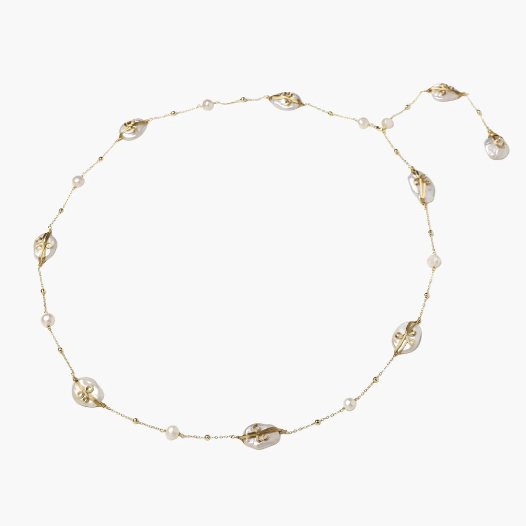 Long gold chain necklace with baroque pearls wrapped in leaf designs and small freshwater pearls spaced along the strand