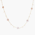 Gold vermeil chain with iridescent star-shaped baroque pearls and small round freshwater pearl drops on cream background.