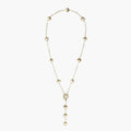 Gold-plated lariat necklace with baroque pearls and textured caps on cream background, showing adjustable Y-shaped design.