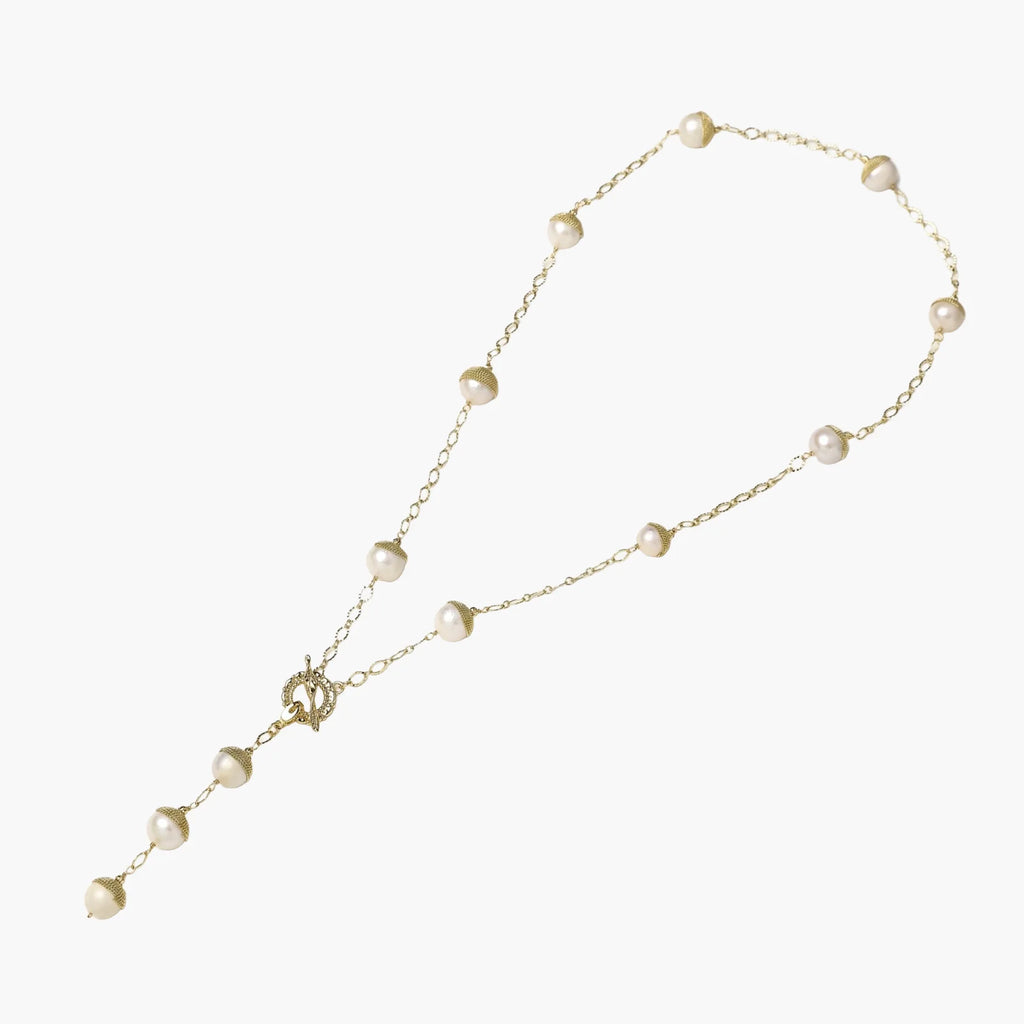 Gold-plated lariat necklace with baroque pearls and textured caps on cream background, showing adjustable Y-shaped design.