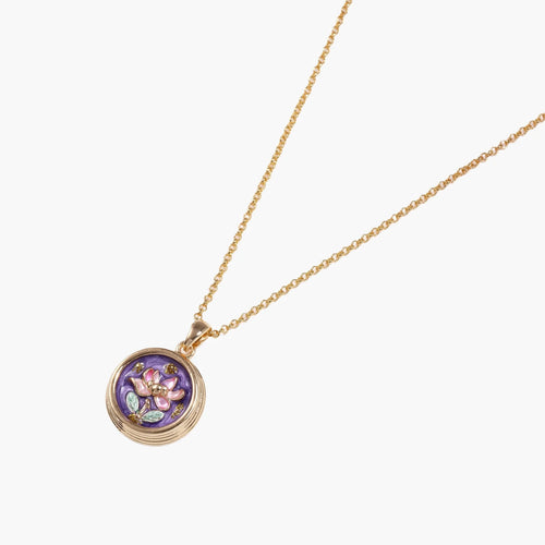 Gold-plated circular pendant with hand-painted purple enamel floral design on delicate chain against cream background