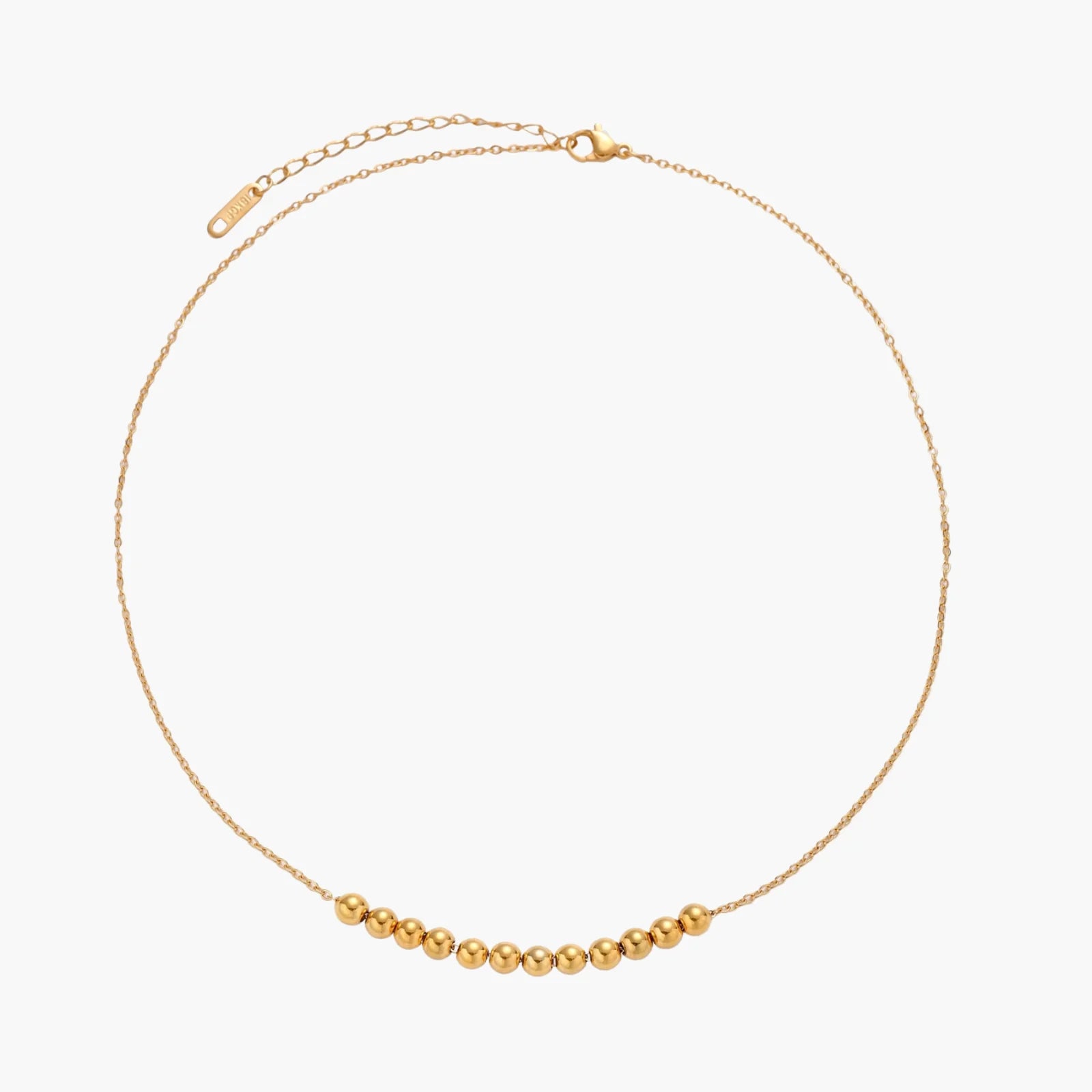 Delicate gold-plated necklace with graduated spherical beads forming gentle smile curve on beige background