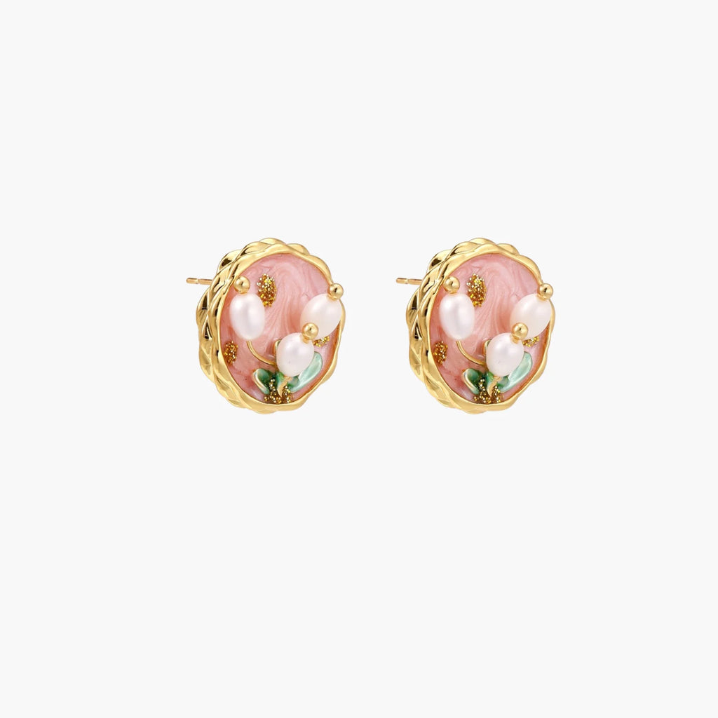 Round stud earrings with pink enamel, three white freshwater pearls, green leaves, and gold-plated braided border