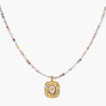 Ornate gold-plated pendant necklace with multicolored gemstone beads in purple, pink and clear tones on white background