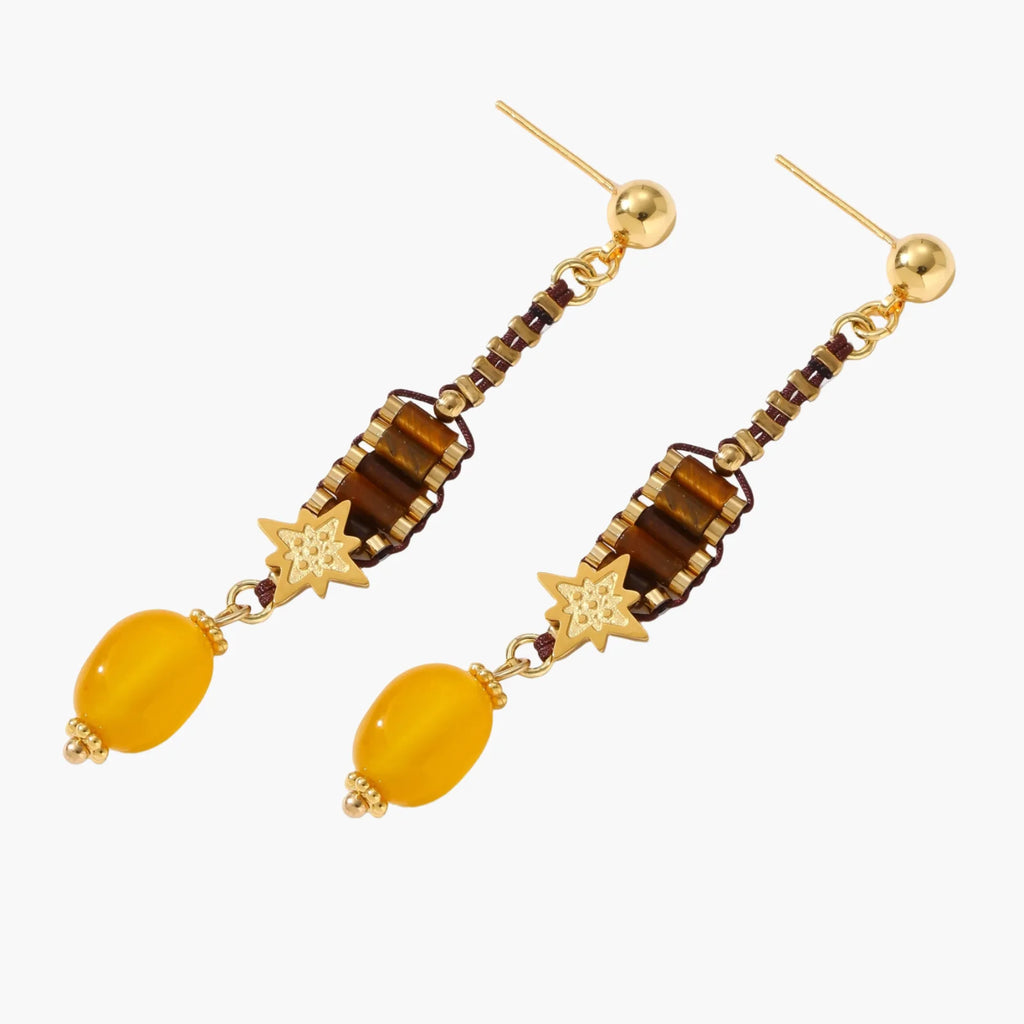 Gold-plated dangle earrings with brown gemstones, star charms, and yellow amber drops on cream background.