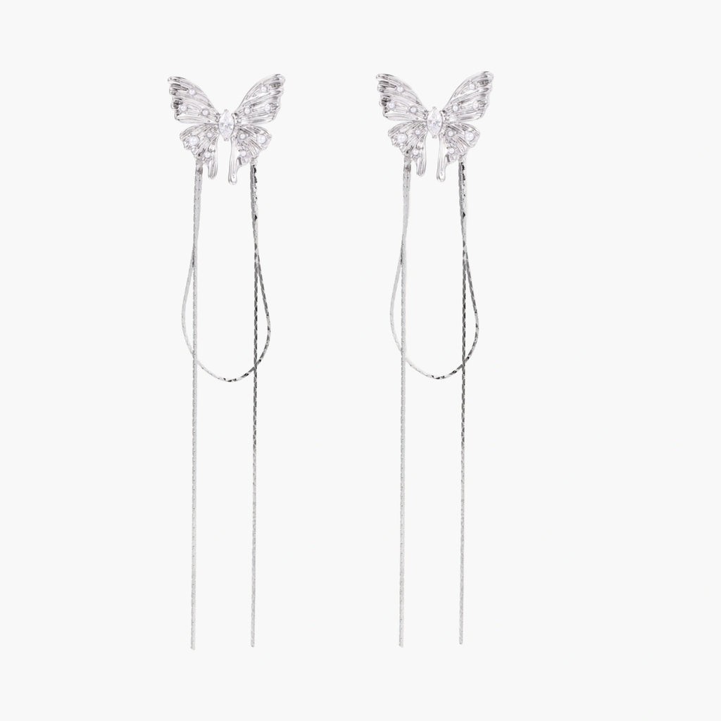 Pair of silver threader earrings with crystal butterfly tops and long chain drops on cream background.