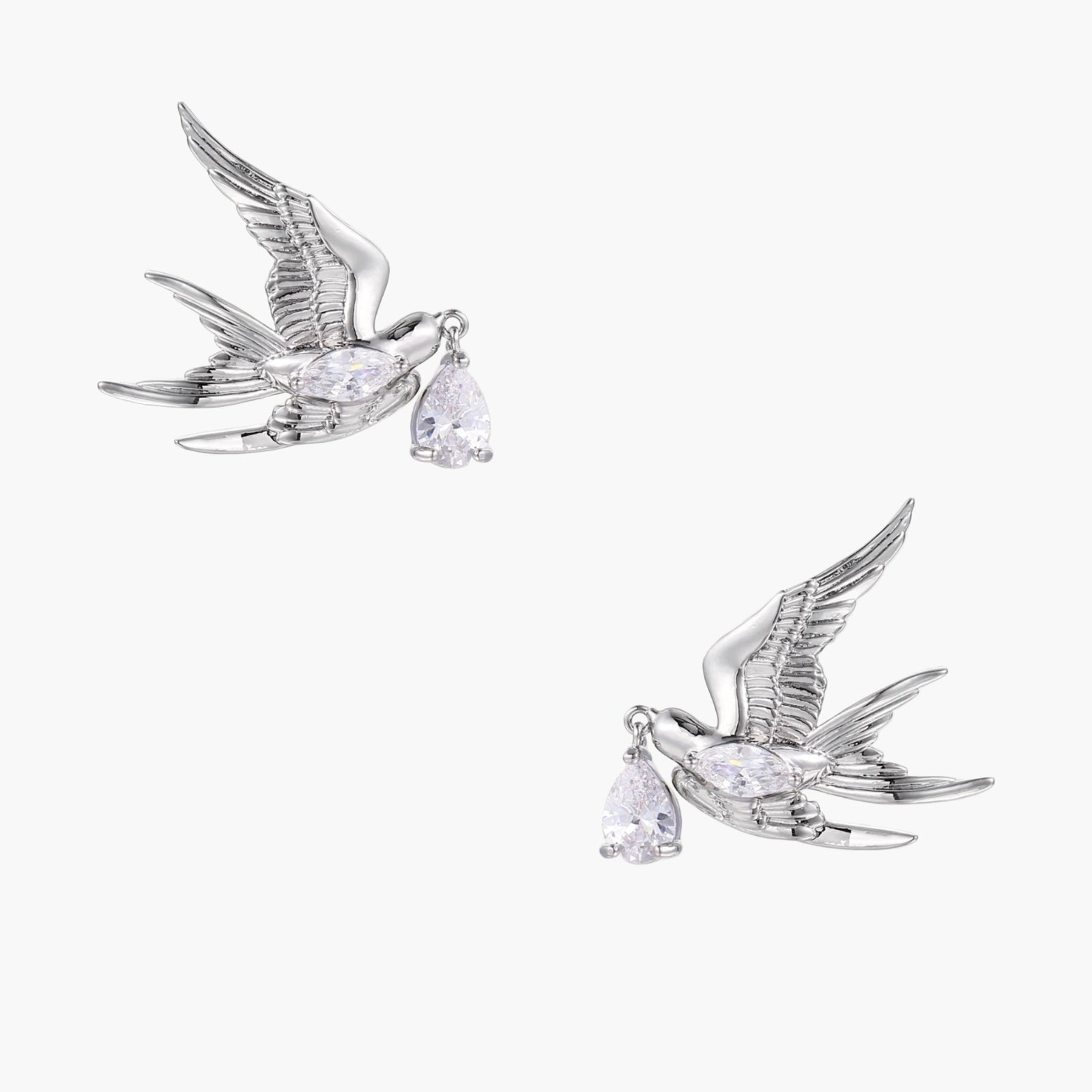 Silver-toned swallow stud earrings with detailed wings carrying teardrop zirconia crystals on white background