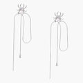 White gold plated spider earrings with pearl body and long threader chains on beige background