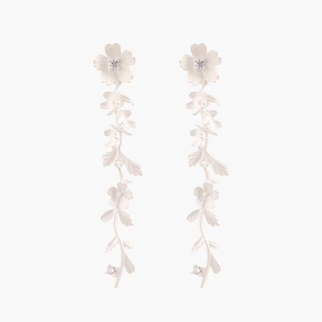 Long sterling silver drop earrings with delicate floral vine design and crystal accents on white background