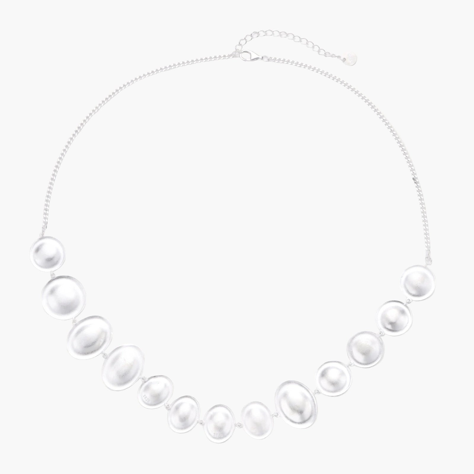Graduated pearl-finish silver discs forming an organic bubble bib necklace on delicate chain against cream background.