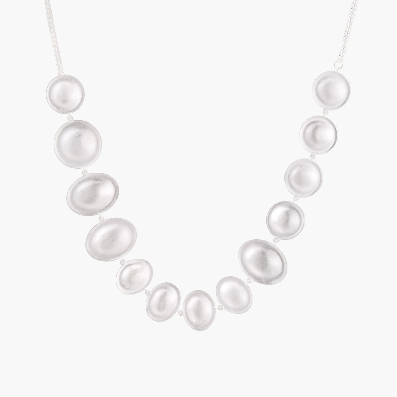 Graduated pearl-finish silver discs forming an organic bubble bib necklace on delicate chain against cream background.