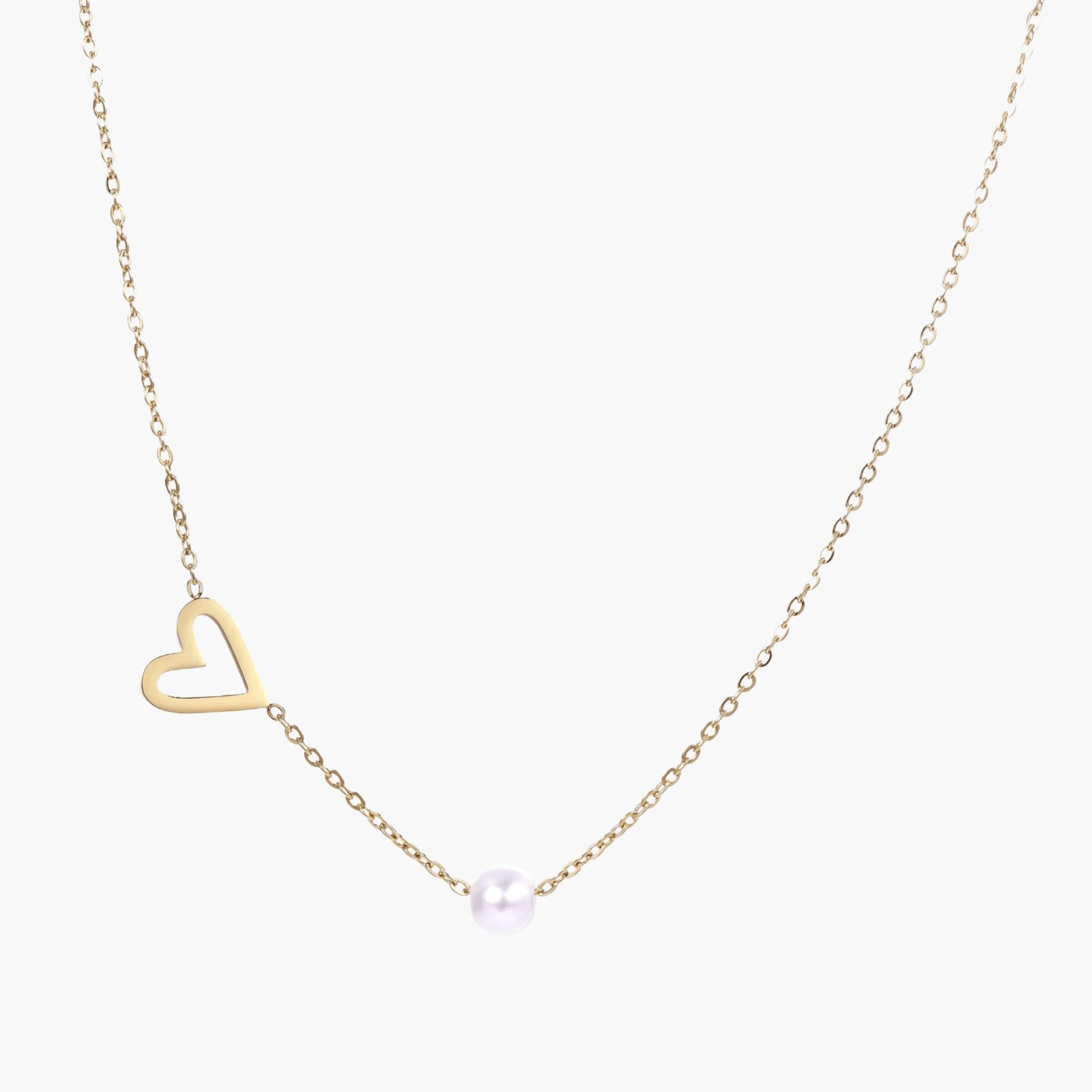 Delicate gold necklace with open heart charm and white pearl bead on fine chain against cream background