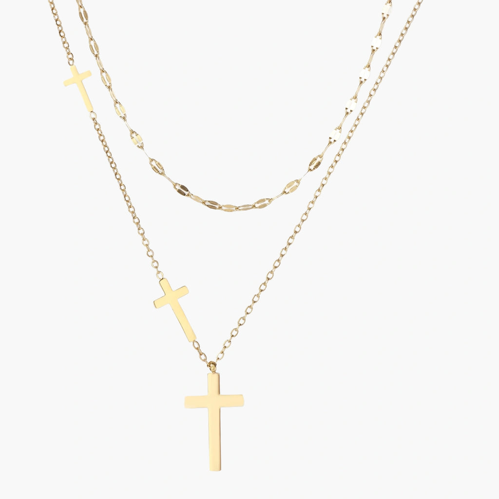 Three-layered gold necklace set with graduated cross pendants in mixed chain styles on white background.