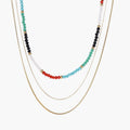 Multi-strand necklace with rainbow quartz beads and gold-plated chains on beige background