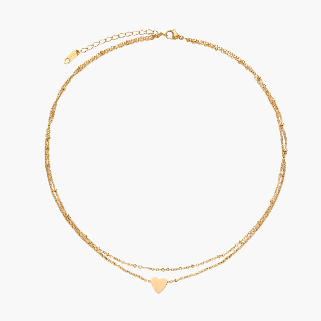 Delicate double-chain gold necklace with tiny heart pendant on cream background