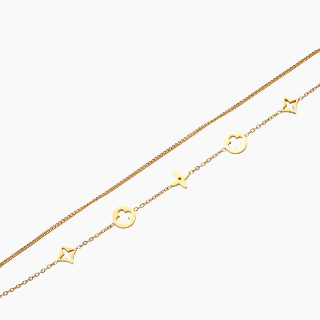 Double-layer gold-plated bracelet with quatrefoil and star charms on cream background, 18K gold finish.