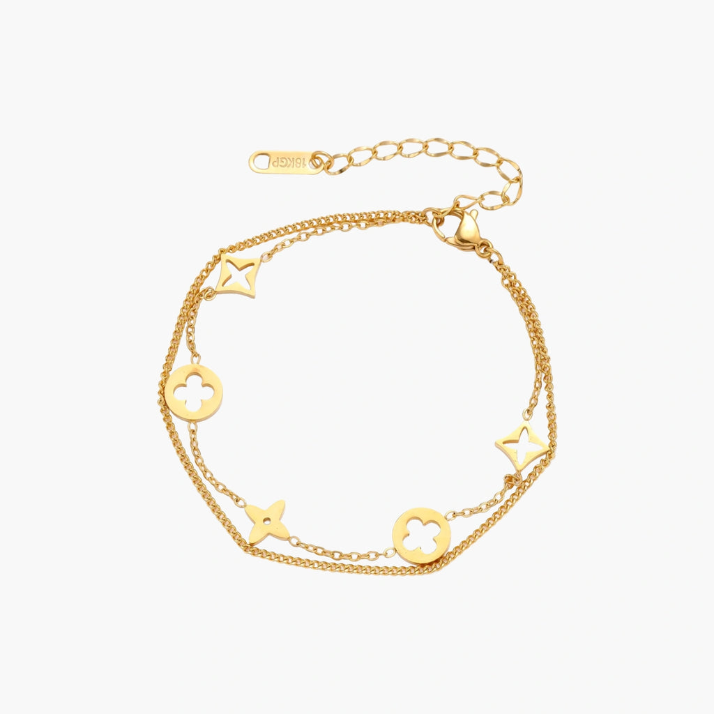 Double-layer gold-plated bracelet with quatrefoil and star charms on cream background, 18K gold finish.