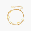 Double-layer gold-plated bracelet with quatrefoil and star charms on cream background, 18K gold finish.