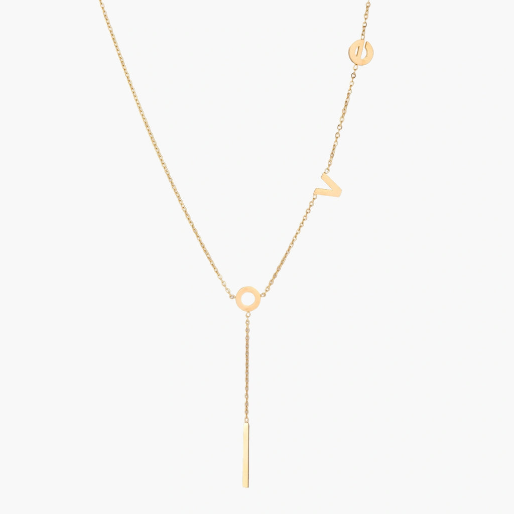 Gold Y-shaped necklace with L-O-V-E letter charms and vertical bar pendant on delicate chain against cream background