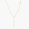 Gold Y-shaped necklace with L-O-V-E letter charms and vertical bar pendant on delicate chain against cream background