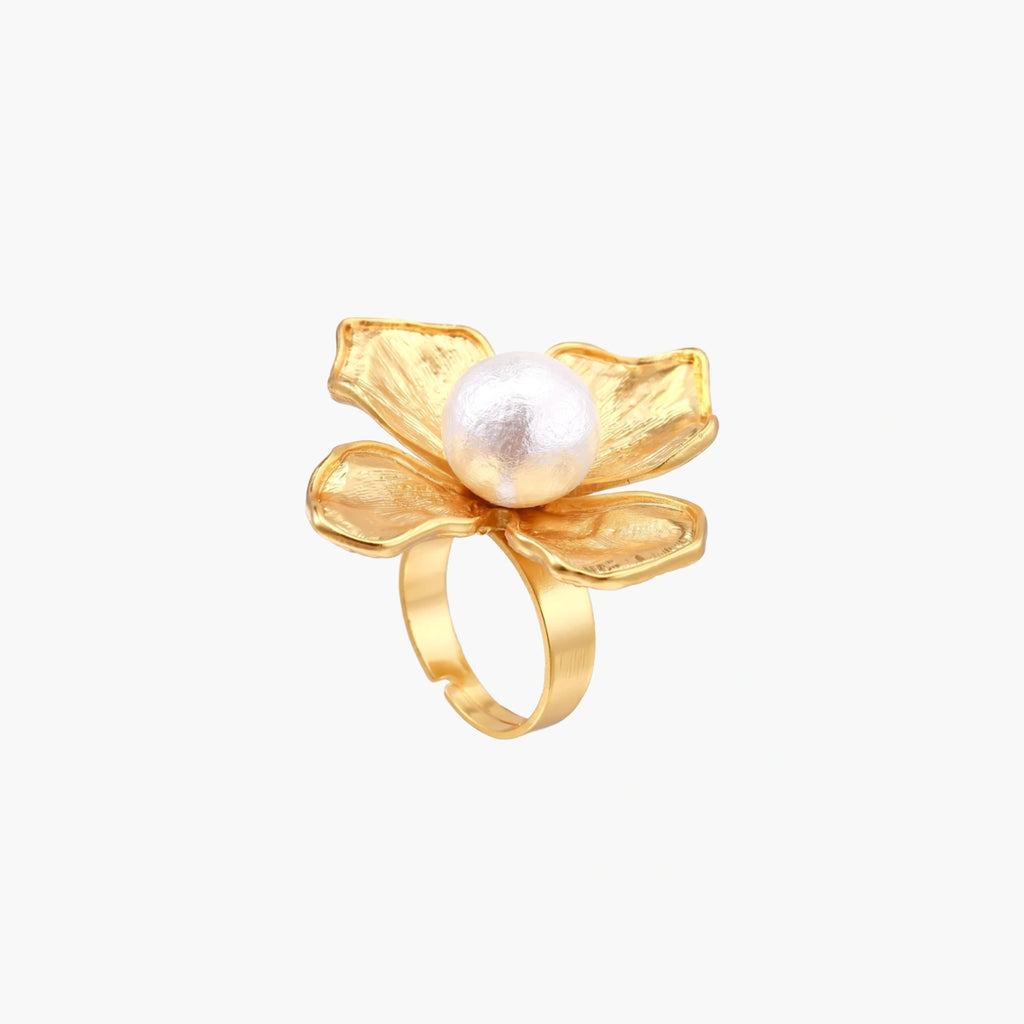 Gold-plated flower ring with textured petals and white cotton pearl center on cream background