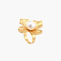 Gold-plated flower ring with textured petals and white cotton pearl center on cream background